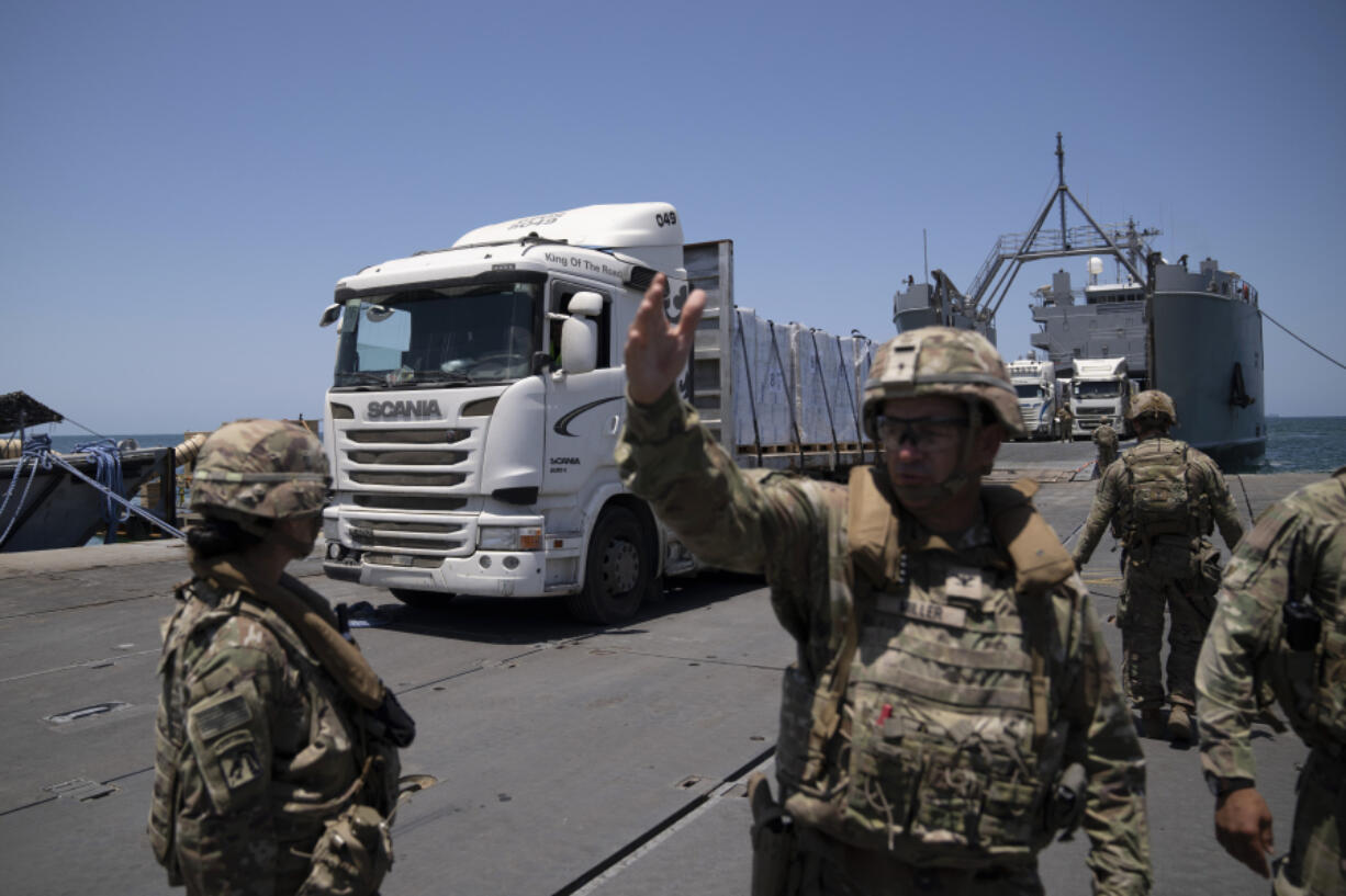 A U.S. Army soldier gestures as trucks loaded with humanitarian aid arrive at the U.S.-built floating pier Trident before reaching the beach on the coast of the Gaza Strip, Tuesday, June 25, 2024.