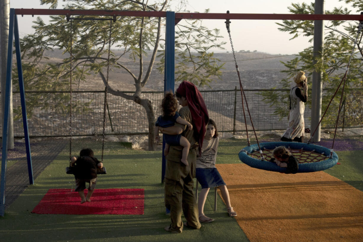 FILE - Women and their children gather in the playground at the end of the day in the settlement outpost of Asa&rsquo;el in the south Hebron hills on Monday, Sept. 4, 2023. The Israeli government has budgeted millions of dollars in security support for small, unofficial Jewish outposts in the Israeli-occupied West Bank, which is enabling the expansion of Jewish settlements while circumventing the official planning process, according to a human rights group.