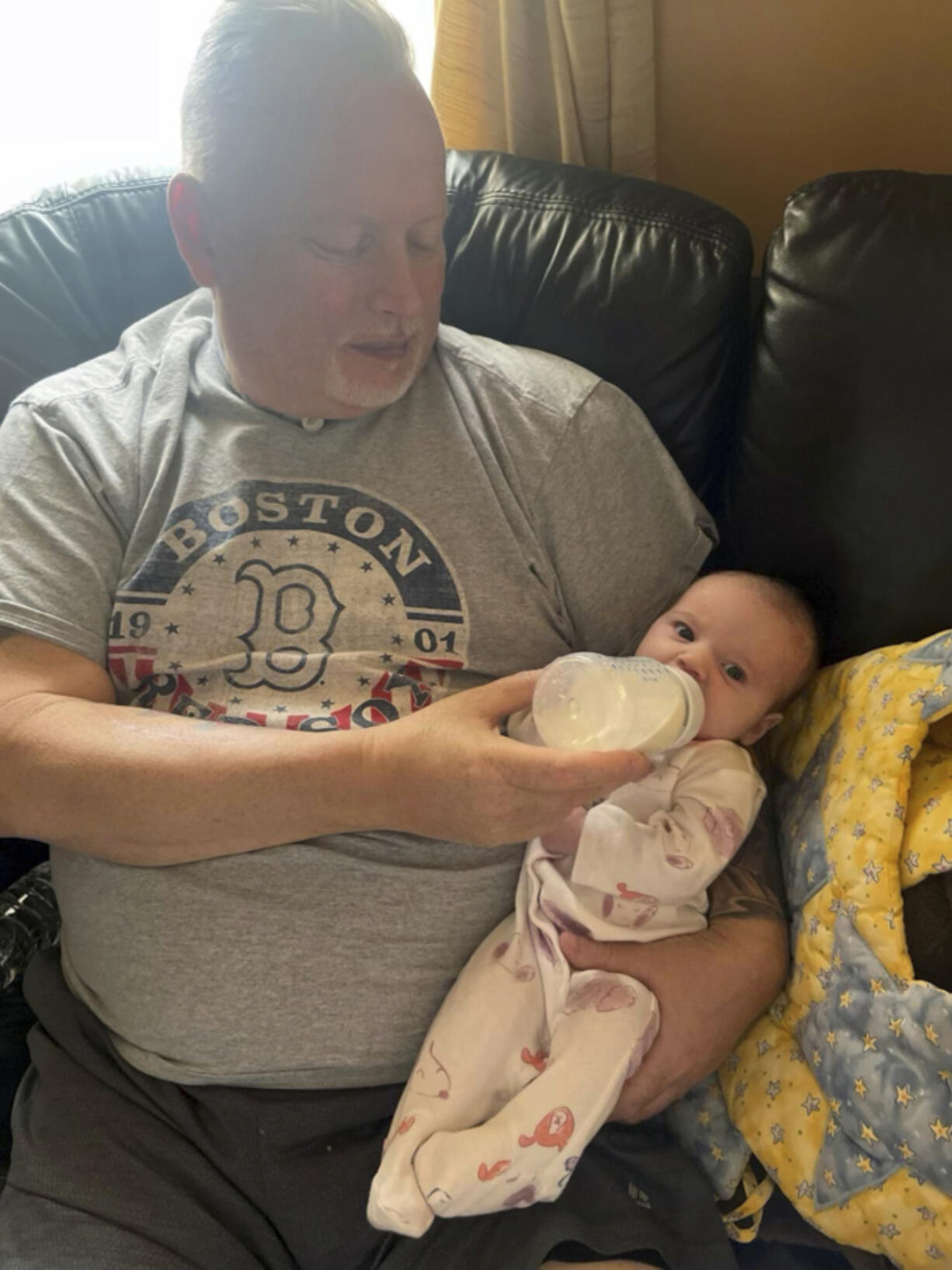 In this photo provided by the family, Marty Kedian holds his granddaughter in Pelham, N.H., on Feb. 26, 2023, before his larynx transplant. Kedian regained his voice after surgeons removed his cancerous larynx and, in a pioneering move, immediately replaced it with a donated one.