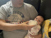 In this photo provided by the family, Marty Kedian holds his granddaughter in Pelham, N.H., on Feb. 26, 2023, before his larynx transplant. Kedian regained his voice after surgeons removed his cancerous larynx and, in a pioneering move, immediately replaced it with a donated one.