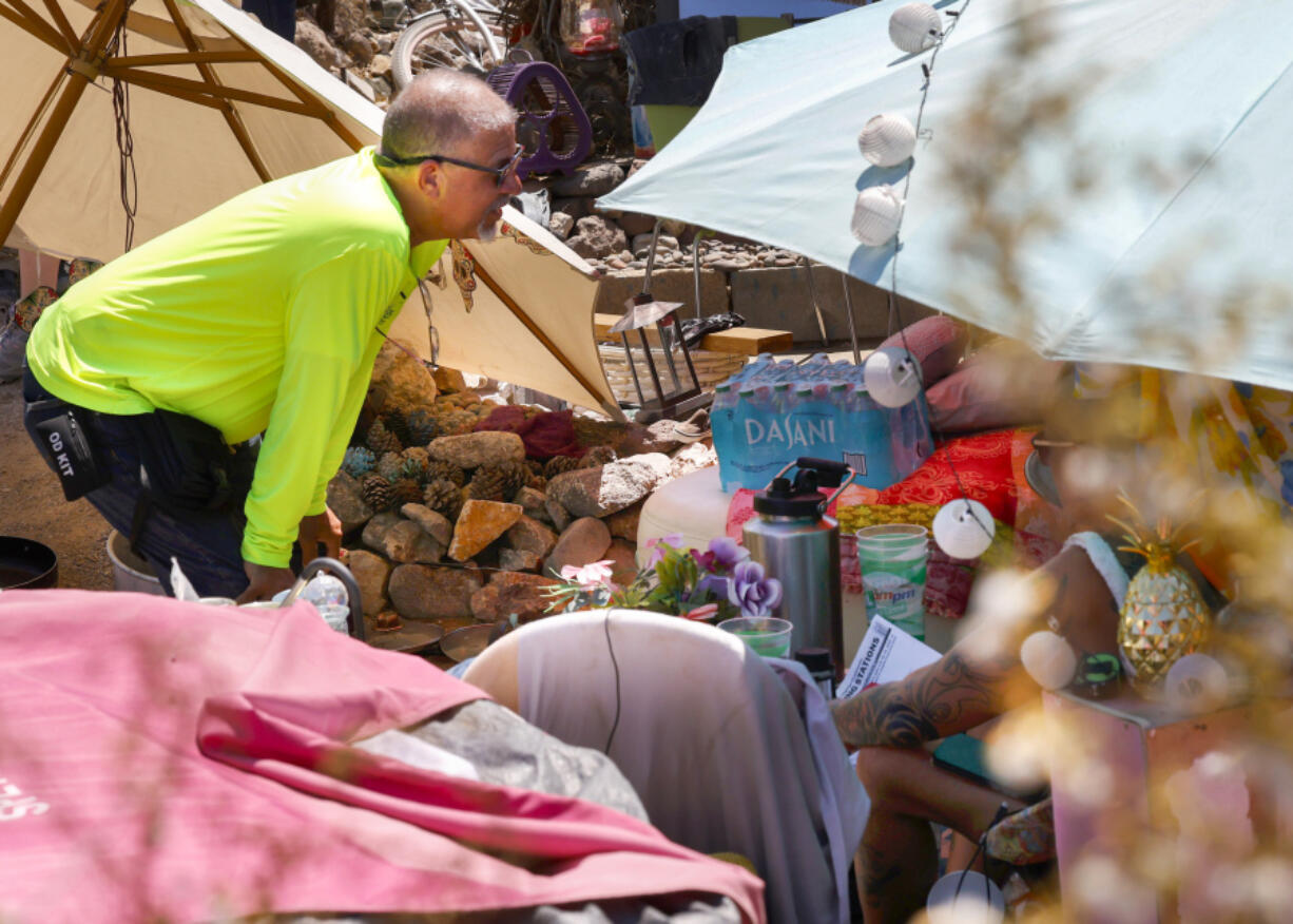 Louis Lacey, director of homeless response teams at Help of Southern Nevada, speaks to a homeless woman to offer water in Las Vegas, on Tuesday, July 9, 2024. Help of Southern Nevada travels the streets with flyers about heat, water and vehicles to transport people to cooling centers.