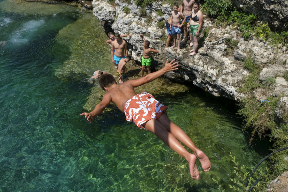 A boy dives into the Cijevna river near Montenegro&rsquo;s capital Podgorica, as temperatures soared to 36 degrees Celsius (96.8 Fahrenheit) on Thursday, July 11, 2024. Weather alerts, forest fires, melting pavement in cities: A sizzling heat wave has sent temperatures in parts of central and southern Europe soaring toward 40 degrees Celsius (104 Fahrenheit) in some places.