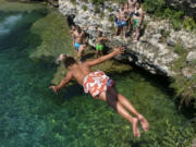 A boy dives into the Cijevna river near Montenegro&rsquo;s capital Podgorica, as temperatures soared to 36 degrees Celsius (96.8 Fahrenheit) on Thursday, July 11, 2024. Weather alerts, forest fires, melting pavement in cities: A sizzling heat wave has sent temperatures in parts of central and southern Europe soaring toward 40 degrees Celsius (104 Fahrenheit) in some places.