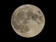 FILE - A plane passes in front of the moon, Aug. 30, 2023, in Chicago. Scientists have confirmed a cave on the moon, not far from where Neil Armstrong and Buzz Aldrin landed 55 years ago this week, and suspect there are hundreds more that could house future astronauts.