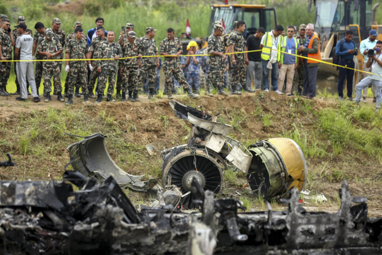 Nepal army personnel stand by a plane crash site at Tribhuvan International Airport in Kathmandu, Nepal, Wednesday, July 24, 2024. State television in Nepal says a plane has slipped off the runway and crashed while trying to take off from the Kathmandu airport.