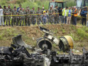 Nepal army personnel stand by a plane crash site at Tribhuvan International Airport in Kathmandu, Nepal, Wednesday, July 24, 2024. State television in Nepal says a plane has slipped off the runway and crashed while trying to take off from the Kathmandu airport.