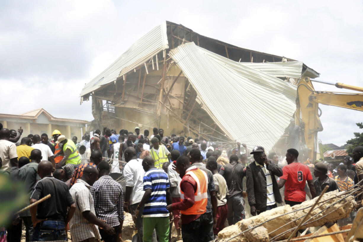 People and rescuers gather Friday at the scene of a collapsed two-story building in Jos, Nigeria. At least 22 students have been killed, authorities said.