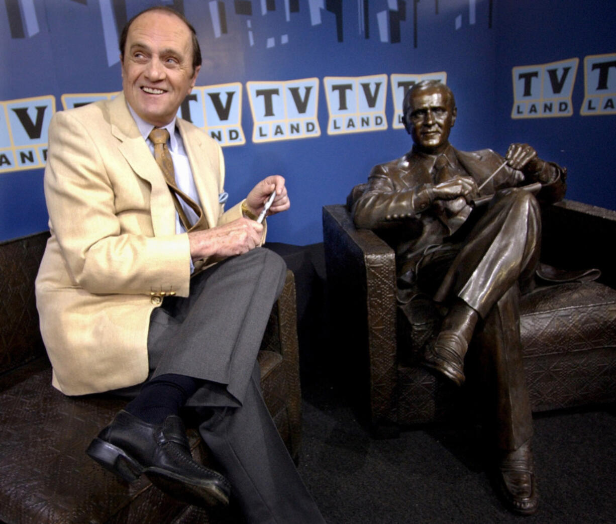 FILE - Actor-comedian Bob Newhart sits with a bronze likeness of Dr. Bob Hartley, the character he played in the 1972-78 sitcom &quot;The Bob Newhart Show,&quot; at the unveiling of the statue in Chicago on July 27, 2004. Newhart, the deadpan master of sitcoms and telephone monologues, died in Los Angeles on Thursday, July 18, 2024. He was 94. (AP Photo/M.