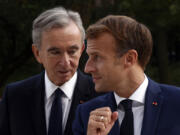 FILE - LVMH luxury group CEO Bernard Arnault, left, and French President Emmanuel Macron arrive at Fondation Louis Vuitton to visit the exhibition &lsquo;The Morozov Collection, Icons of Modern Art&rsquo; in Paris, Tuesday, Sept. 21, 2021. With a major sponsorship role aimed at burnishing the image of the Paris 2024 Summer Olympic Games and the French capital, it&rsquo;s a new chapter in LVMH&rsquo;s specialty of selling exclusivity at a grand scale under its chair and CEO, Arnault.
