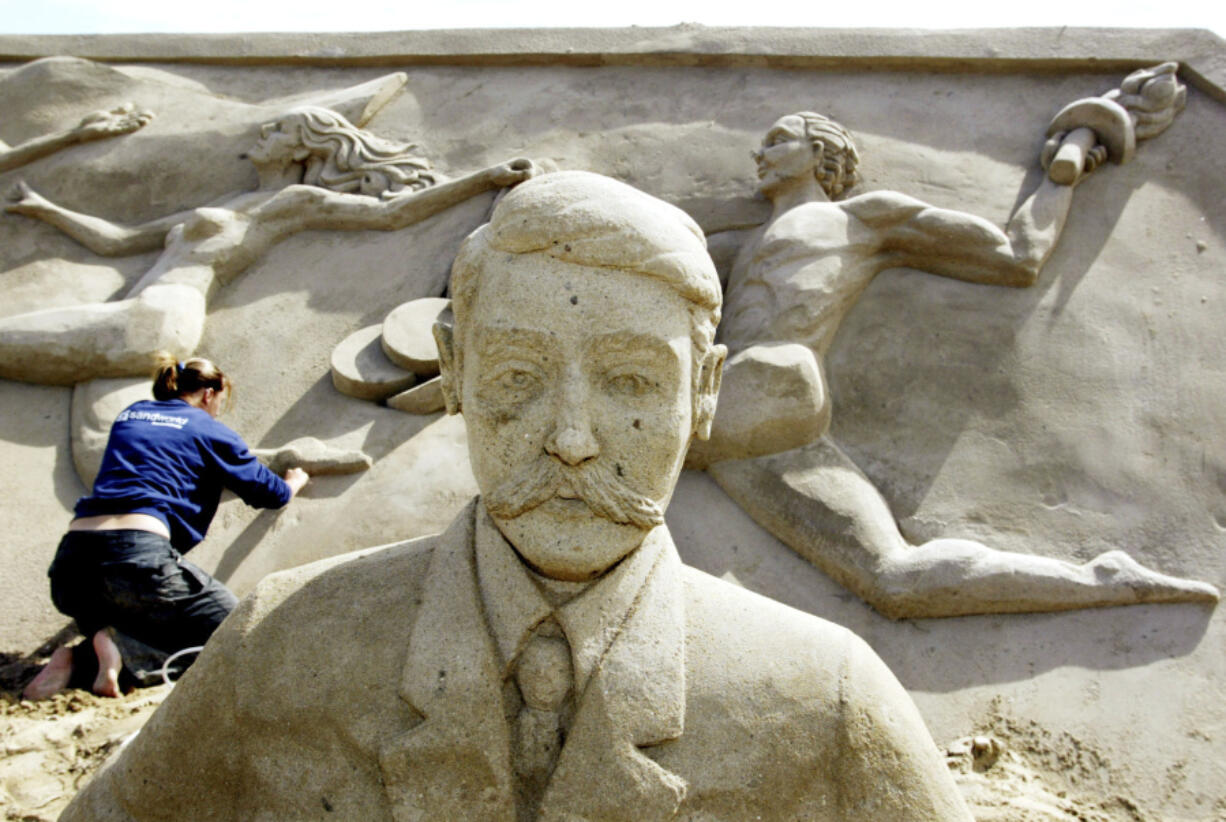 Carver Maaike Huizinga from the Netherlands gives a final touch July 6, 2004, to the sand sculpture of sports people behind Pierre de Coubertin, the founder of the modern Olympic Games, in the &ldquo;Olympic Stadium Travemuende&rdquo; at the beach of the Luebeck Bay in Luebeck-Travemuende, Germany.