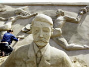 Carver Maaike Huizinga from the Netherlands gives a final touch July 6, 2004, to the sand sculpture of sports people behind Pierre de Coubertin, the founder of the modern Olympic Games, in the &ldquo;Olympic Stadium Travemuende&rdquo; at the beach of the Luebeck Bay in Luebeck-Travemuende, Germany.