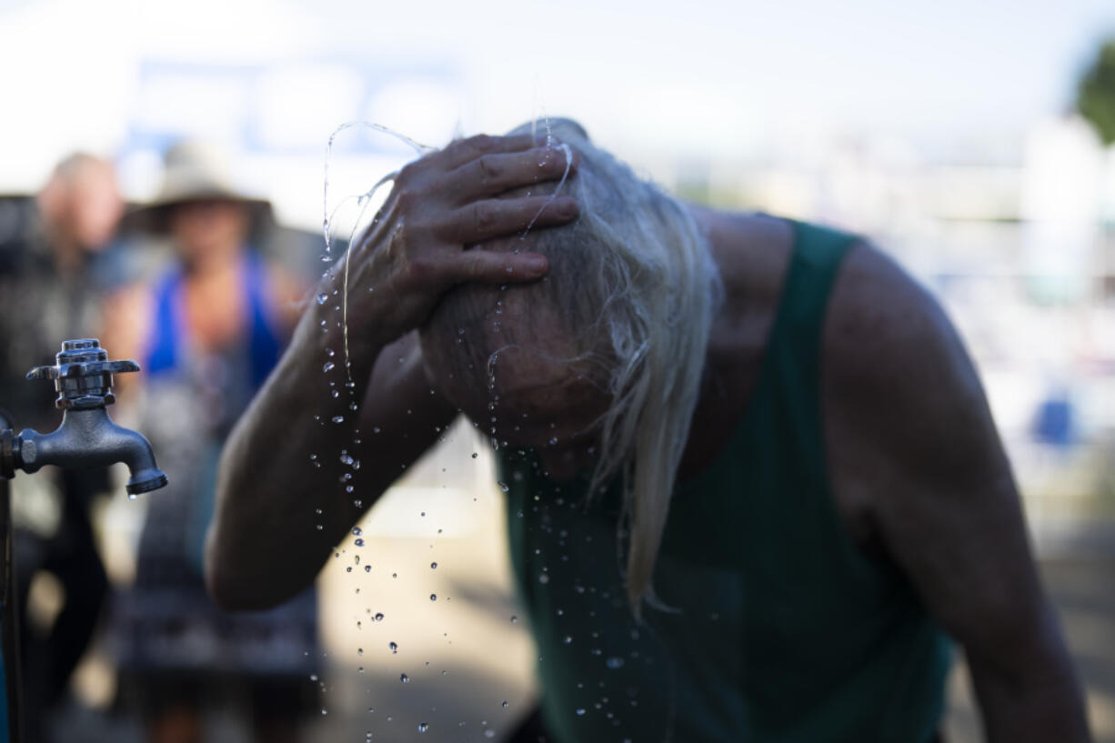 A person cools off during the Waterfront Blues Festival on Friday, July 5, 2024, in Portland, Ore. A slow-moving and potentially record-setting heat wave is spreading across the Western U.S., sending many residents in search of a cool haven from the dangerously high temperatures.