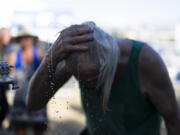 A person cools off during the Waterfront Blues Festival on Friday, July 5, 2024, in Portland, Ore. A slow-moving and potentially record-setting heat wave is spreading across the Western U.S., sending many residents in search of a cool haven from the dangerously high temperatures.