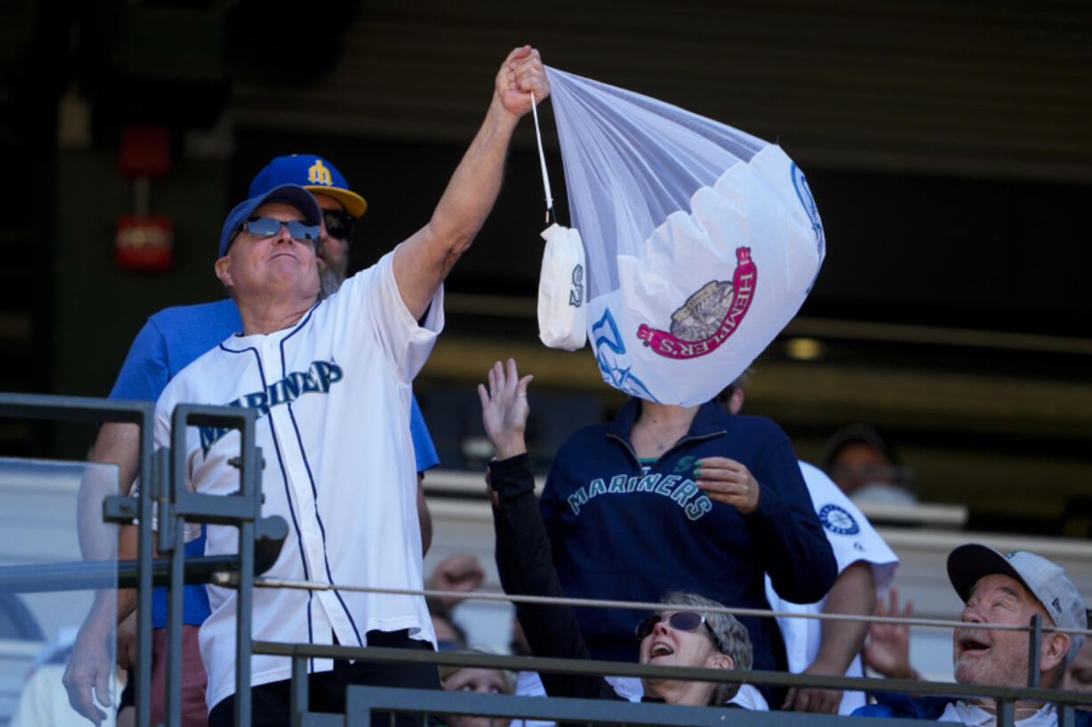 A fan holds up a hot dog attached to a parachute after catching it during a &ldquo;Hot Dogs from Heaven&rdquo; promotion after the bottom of the seventh inning of a baseball game between the Seattle Mariners and the Baltimore Orioles, Thursday, July 4, 2024, in Seattle.