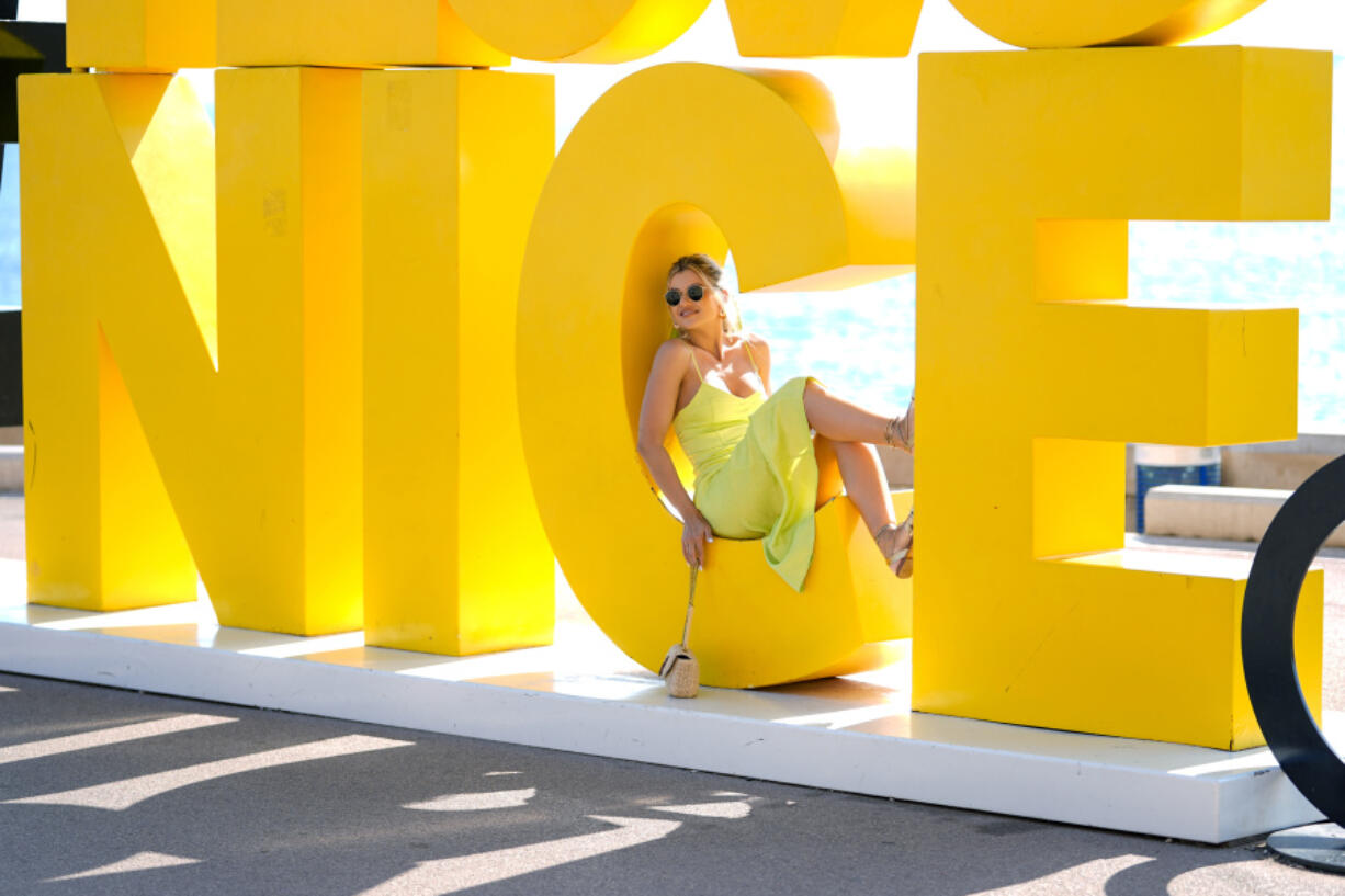 A tourist from Romania poses for a photograph on a sign along the Nice oceanfront July 23 ahead of the 2024 Summer Olympics. Nice will host 6 soccer matches during the summer Olympics.