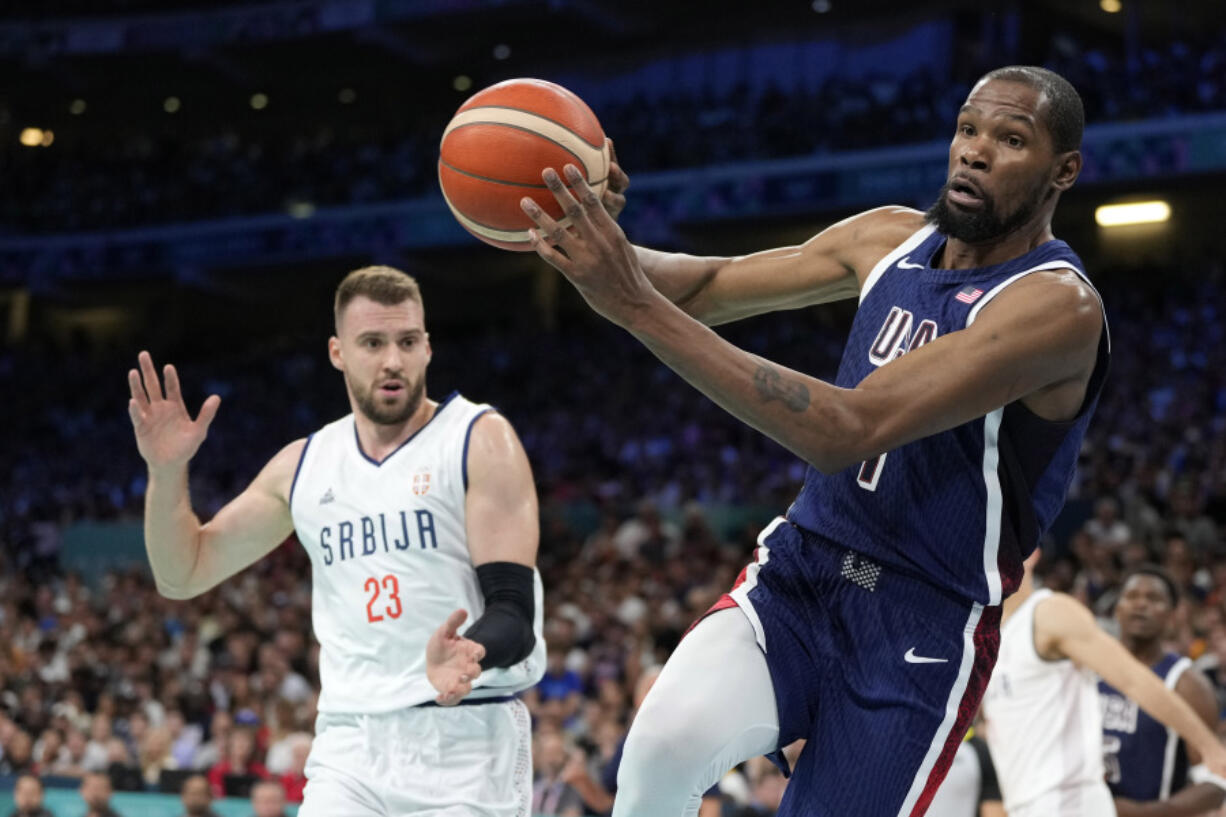 Kevin Durant, right, of the United States, passes the ball as he heads out of bounds while under pressure from Marko Guduric, of Serbia, in a men&#039;s basketball game at the 2024 Summer Olympics, Sunday, July 28, 2024, in Villeneuve-d&#039;Ascq, France.