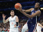 Kevin Durant, right, of the United States, passes the ball as he heads out of bounds while under pressure from Marko Guduric, of Serbia, in a men&#039;s basketball game at the 2024 Summer Olympics, Sunday, July 28, 2024, in Villeneuve-d&#039;Ascq, France.