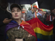 A woman soldier wrapped in the LGBTQ+ flag attends a Pride march in Kyiv, Ukraine, Sunday, June 16, 2024.