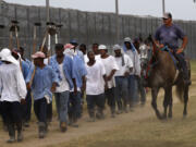 In this Aug. 18, 2011 photo, prison guards ride horses that were broken by inmates as they return from farm work detail at the Louisiana State Penitentiary in Angola, La. In September, several incarcerated workers along with the New Orleans-based advocacy group Voice of the Experienced filed a class-action lawsuit calling for an end to the farm line, and accusing the state of cruel and unusual punishment. But as temperatures soared in May, the men asked the court in an emergency filing to stop work during extreme heat.