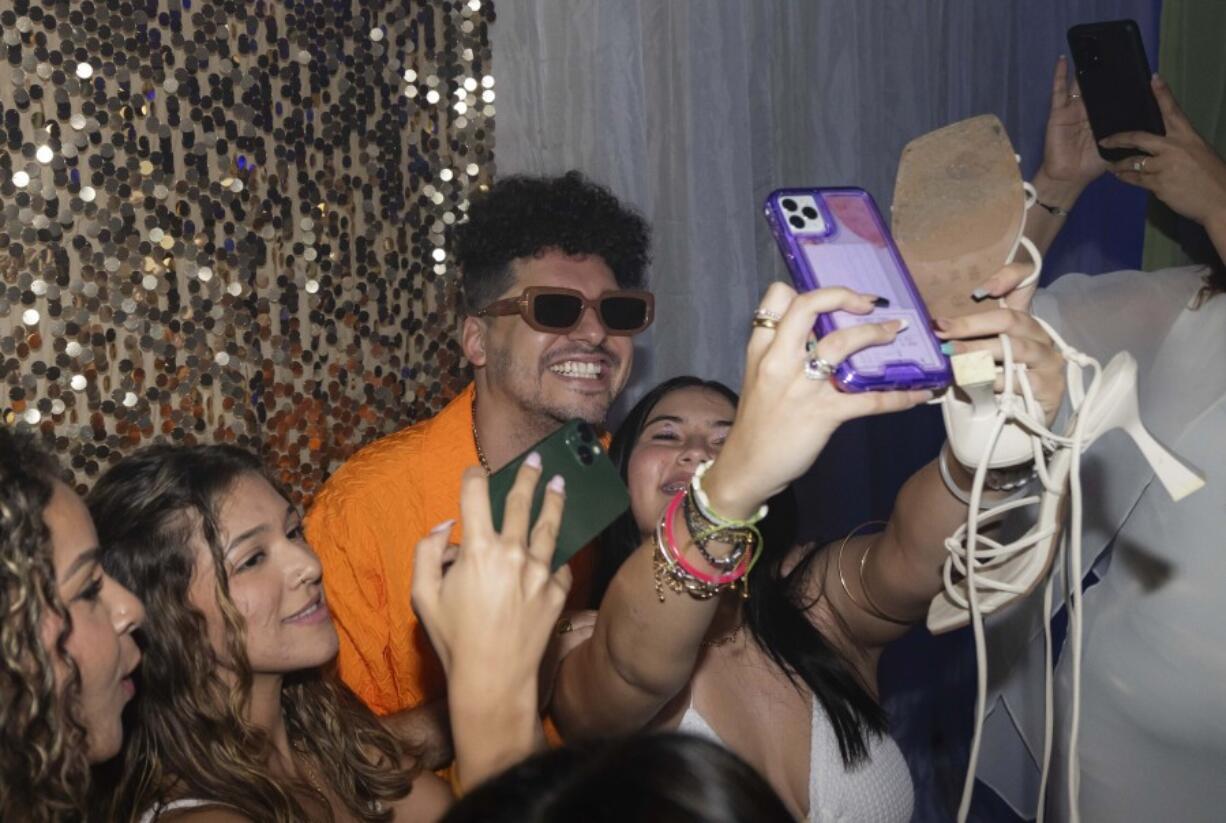 Dr. Pedro Juan V&aacute;zquez, better known by his stage name PJ Sin Suela, poses for group selfies at a high school prom in Camuy, Puerto Rico, Thursday, June 6, 2024.