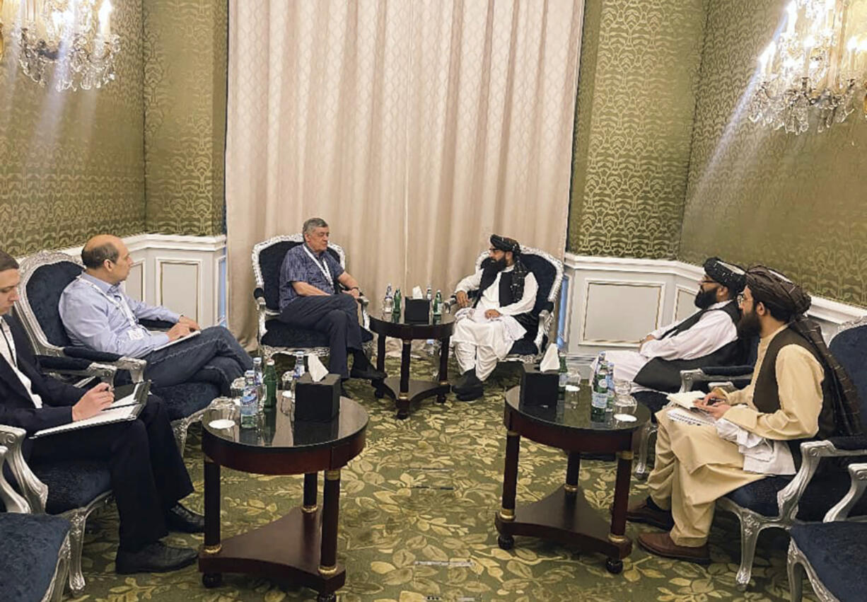 In this photo released by the Taliban Spokesman Office, Zabihullah Mujahid, the chief spokesman for the Taliban government who leads the Taliban delegation, center right, speaks with Russian Presidential Envoy to Afghanistan Zamir Kabulov, during a meeting in Doha, Qatar, Sunday, June 30, 2024. A Taliban delegation is attending a United Nations-led meeting in Qatar on Afghanistan after organizers said women would be excluded from the gathering. The two-day meeting is the third U.N.-sponsored gathering on the Afghan crisis.