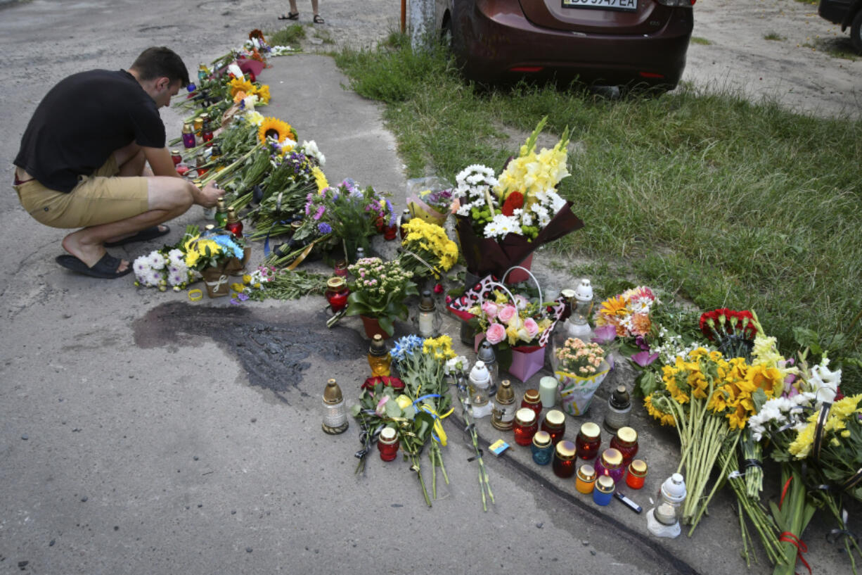 People lay flowers and light candles at a makeshift memorial in tribute to former Ukrainian nationalist lawmaker Iryna Farion at the place of her murder in Lviv, Ukraine, Saturday, July 20, 2024. A former Ukrainian nationalist lawmaker who often made outspoken statements defending the Ukrainian language has died after being shot by a gunman in her home city of Lviv, authorities said.