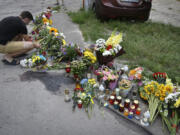 People lay flowers and light candles at a makeshift memorial in tribute to former Ukrainian nationalist lawmaker Iryna Farion at the place of her murder in Lviv, Ukraine, Saturday, July 20, 2024. A former Ukrainian nationalist lawmaker who often made outspoken statements defending the Ukrainian language has died after being shot by a gunman in her home city of Lviv, authorities said.