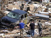 FILE - Local residents walk among the debris from tornado damaged homes, May 22, 2024, in Greenfield, Iowa. Record flooding and powerful tornadoes ravaged parts of Iowa for weeks this spring, destroying or damaging thousands of homes, closing roads and bridges and costing over $130 million in infrastructure damage, officials said Thursday, July 11.