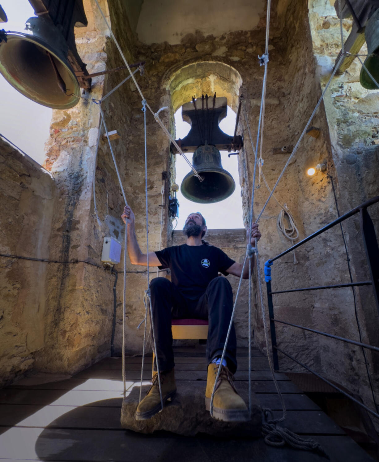 Sitting in a chair with ropes looped around both feet and hands, Joan Carles Osuna, a student of the Vall d&rsquo;en Bas School of Bell Ringers, performs June 29 playing all four bronze bells at the church bell tower of the12th-century Sant Rom&agrave; church, at the village of Joanetes, about two hours north of Barcelona, Spain.