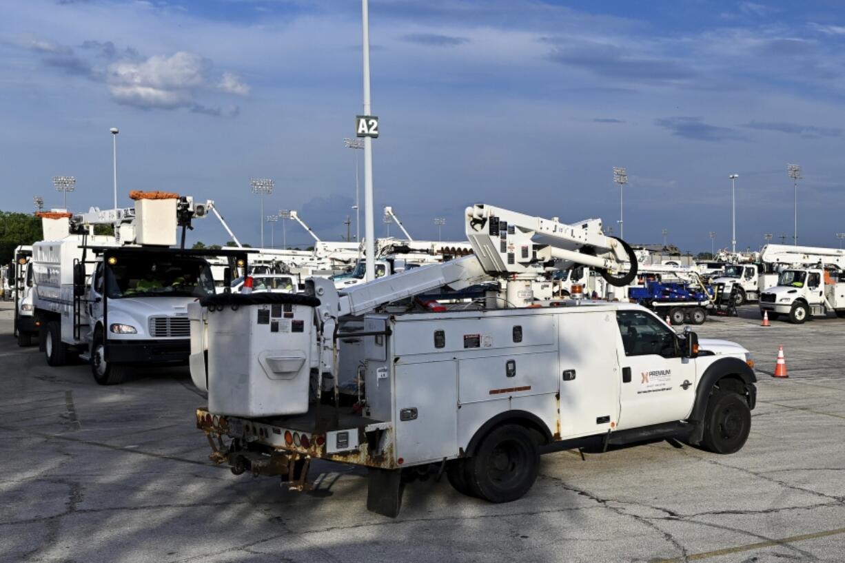 Utility trucks sit parked at a CenterPoint Energy staging center at the Houston Race Track in Houston, Wednesday, July 10, 2024. Millions of residents lost power after Hurricane Beryl made landfall.