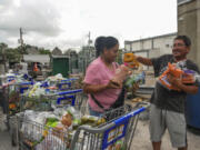 East End residents Laura and Jose Galvan sift through perishable foods that were left outside of a Kroger due to power outages from the recent Hurricane Beryl that made landfall in Houston on Tuesday, July 9, 2024.