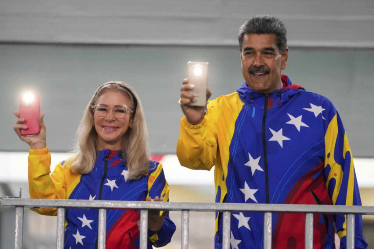 President Nicolas Maduro and First Lady Cilia Flores turn on their mobile phone flashlights after voting in the presidential elections in Caracas, Venezuela, Sunday, July 28, 2024. Maduro is seeking re-election for a third term.