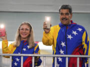 President Nicolas Maduro and First Lady Cilia Flores turn on their mobile phone flashlights after voting in the presidential elections in Caracas, Venezuela, Sunday, July 28, 2024. Maduro is seeking re-election for a third term.