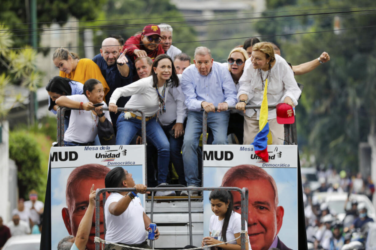 Opposition leader Maria Corina Machado, center left, and opposition presidential candidate Edmundo Gonzalez bend down to avoid cables as they ride on the top of a truck during a protest against official presidential election results declaring President Nicolas Maduro the winner in Caracas, Venezuela, Tuesday, July 30, 2024, two days after the vote.