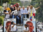 Opposition leader Maria Corina Machado, center left, and opposition presidential candidate Edmundo Gonzalez bend down to avoid cables as they ride on the top of a truck during a protest against official presidential election results declaring President Nicolas Maduro the winner in Caracas, Venezuela, Tuesday, July 30, 2024, two days after the vote.