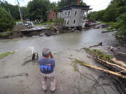 FILE - Rick Gordon, of Plainfield, Vt., looks at what remains of Mill Street and an apartment building after remnants of Hurricane Beryl caused flooding and destruction, Friday, July 12, 2024, in Plainfield. On Wednesday, July 24, Vermont opened the first of four flood recovery centers while officials waited to find out whether the state qualifies for federal help through a disaster declaration.