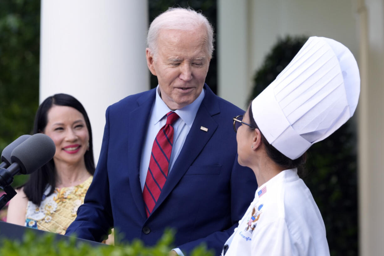 FILE - President Joe Biden looks toward White House Executive Chef Cris Comerford as actor Lucy Liu watches in the Rose Garden of the White House in Washington, May 13, 2024, during a reception celebrating Asian American, Native Hawaiian, and Pacific Islander Heritage Month. Comerford has retired after nearly three decades of making meals and cooking up state dinners for five different presidents and their families.