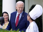 FILE - President Joe Biden looks toward White House Executive Chef Cris Comerford as actor Lucy Liu watches in the Rose Garden of the White House in Washington, May 13, 2024, during a reception celebrating Asian American, Native Hawaiian, and Pacific Islander Heritage Month. Comerford has retired after nearly three decades of making meals and cooking up state dinners for five different presidents and their families.