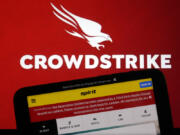 The logo for CrowdStrike and a Spirit Airlines webpage are shown on a computer screen and mobile phone screen, in New York, Friday, July 19, 2024. A global technology outage grounded flights, knocked banks offline and media outlets off air after a faulty software update disrupted companies and services around the world and highlighted their dependence on just a handful of providers.