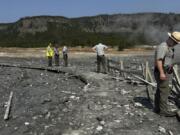 In this photo released by the National Park Service, park staff assess the damage to Biscuit Basin boardwalks after a hydrothermal explosion at Biscuit Basin in Yellowstone National Park, Wyo., Tuesday, July 23, 2024.