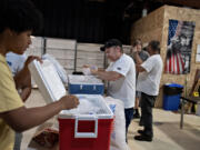 Volunteer Keith Dewing, left, and David Leitz prepare coolers of ice water for guests at the Living Hope Church cooling center July 8.