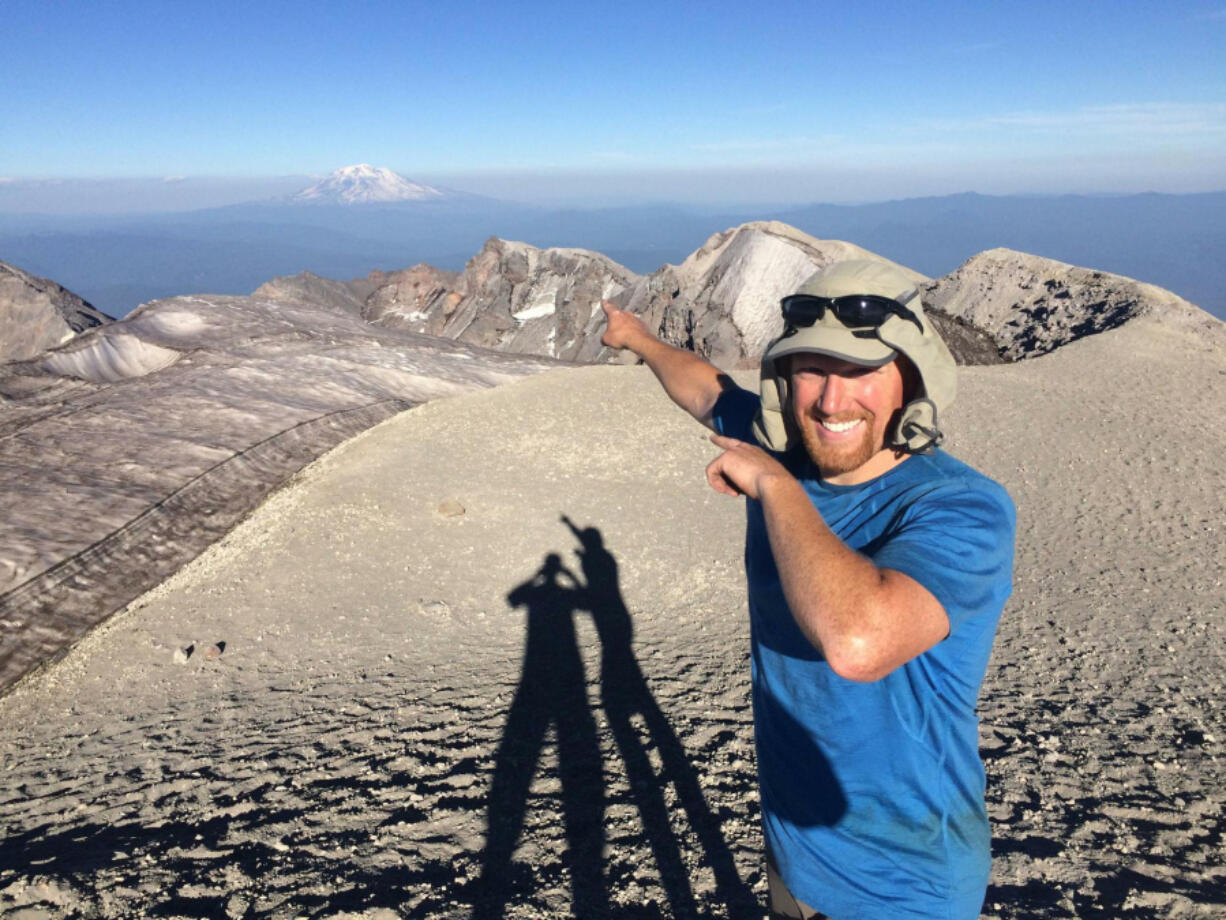 Nick Burson points to Mount Adams fom the summit of Mount St. Helens during a trip with Marc McPherson, when the two climbing pair scaled Washington&rsquo;s five volcanic peaks in five days. The pair set a new record last month, making the trip in less than four days.