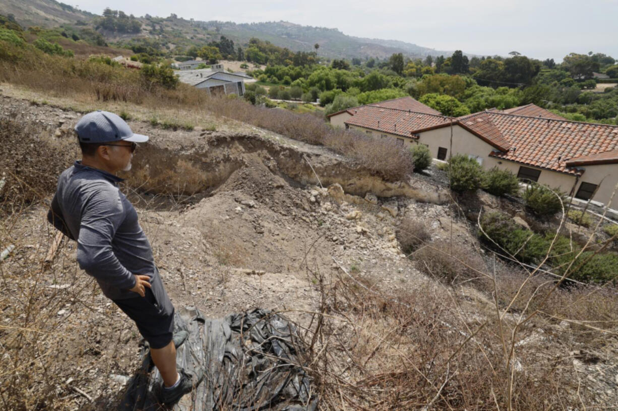 Homeowner Mike Hong views a large fissure that has continued to grow since February damaging a neighbor&Ccedil;&fnof;&Ugrave;s Portuguese Bend home. The landslide damage in the area has accelerated following two winters of heavy rain in Rancho Palos Verdes. (Allen J.