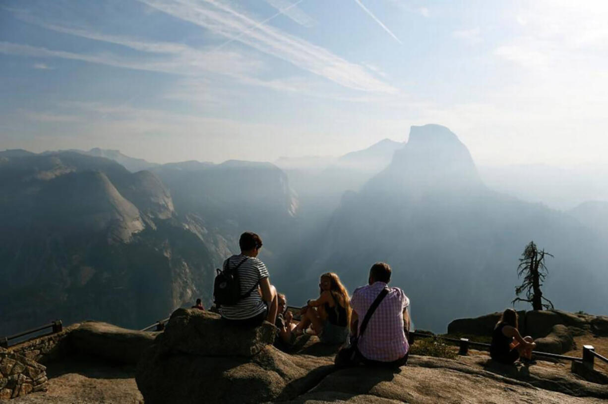 Visitors enjoy a hazy view of Half Dome from Glacier Point at Yosemite National Park Yosemite in California.