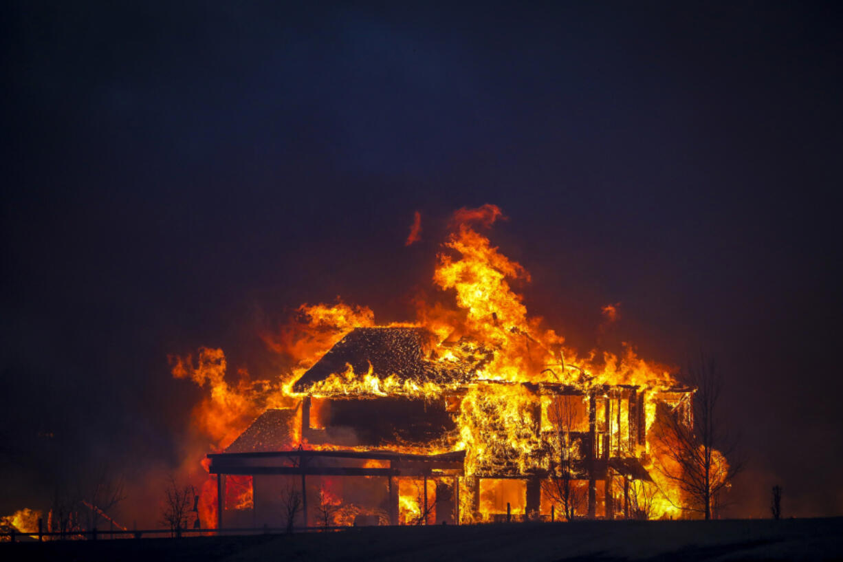 A home burns after a fast-moving wildfire swept through the area in the Centennial Heights neighborhood of Louisville, Colorado on Thursday, Dec. 30, 2021. U.S. homeowners&Ccedil;&fnof;&Ugrave; wildfire and flood risks are underinsured by $28.7 billion a year.