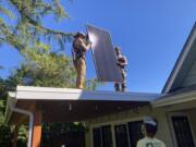 Contractors install solar panels on a house in Oregon. Under proposed rules for the state’s redo of the Climate Protection Program, fossil fuel companies could offset 15% to 20% of their greenhouse gas emissions by investing in projects that help reduce emissions, such as expanding at home solar operations in low-income neighborhoods and the purchase of electric vehicles and charging stations for nonprofits.