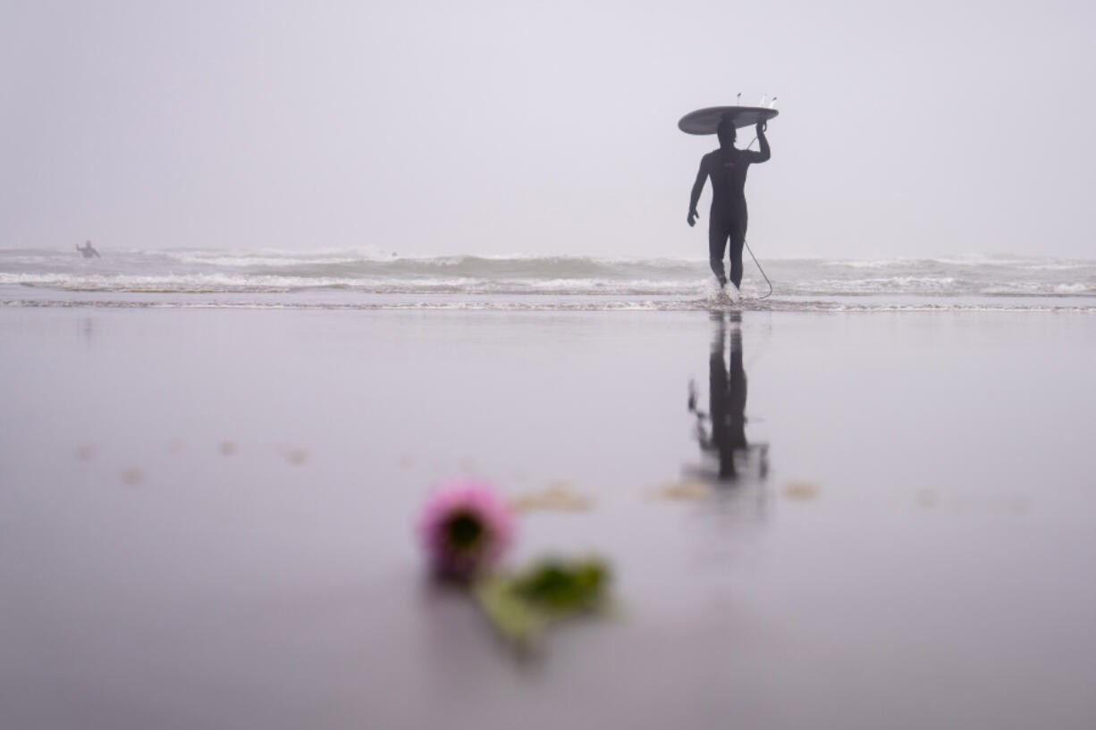 Caleb Carr makes his way into the ocean for more wave-catching after a Waves of Grief event at Roosevelt Beach in Copalis, Washington, on July 14, 2024. Every second Sunday of the month, the group comes together for peer listening and surfing. Carr spoke on his loss of playfulness and childlikeness when coming into adulthood.