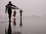 Bill Carver, Rochel Padron and Riel Padron, 11, make their way into the water during a Waves of Grief session at Roosevelt Beach in Copalis, Washington, on July 14, 2024. Participants are invited to surf, but it&Ccedil;&fnof;&Ugrave;s not necessary. Some brought boogie boards and others, like Rochel, just enjoyed walking along the water.