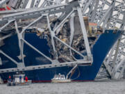 Boats are dwarfed by the twisted structure from the Francis Scott Key Bridge draped across the container ship Dali.