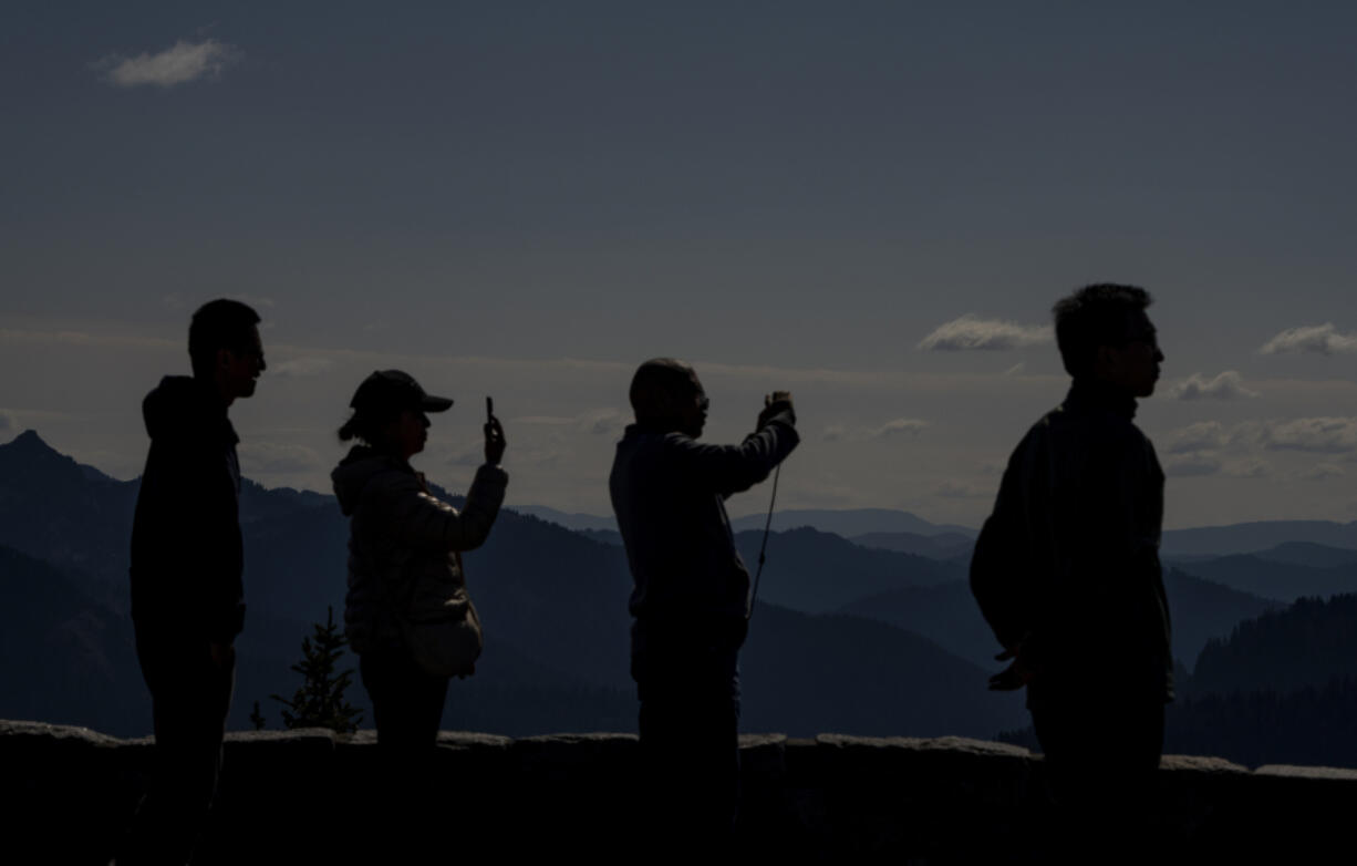 Visitors take photos at Sunrise Point, with the Cascade Range in the background, Thursday, Sept. 21, 2023, at Mount Rainier National Park, near Sunrise, Wash.